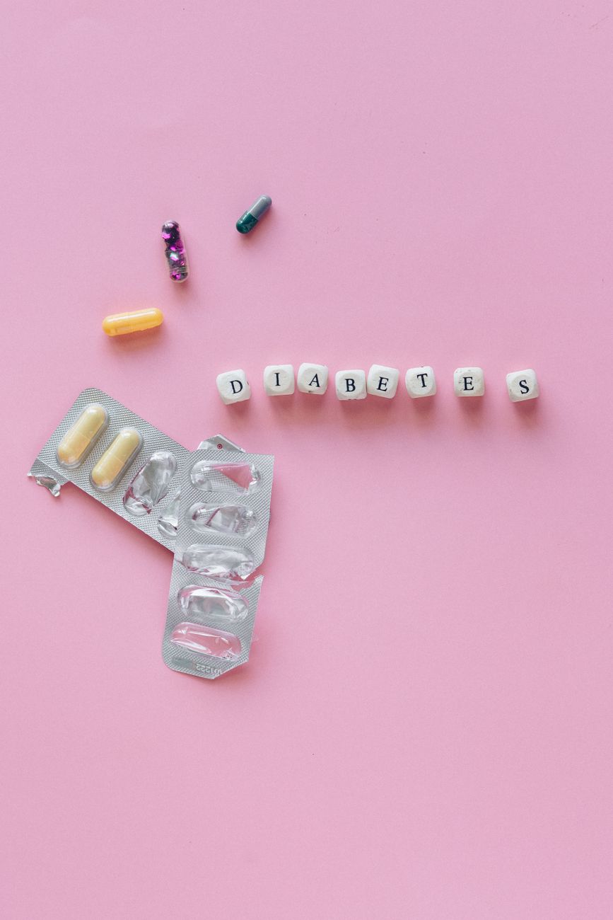 Creative arrangement of diabetes pills on a pink background, symbolizing medication and treatment.