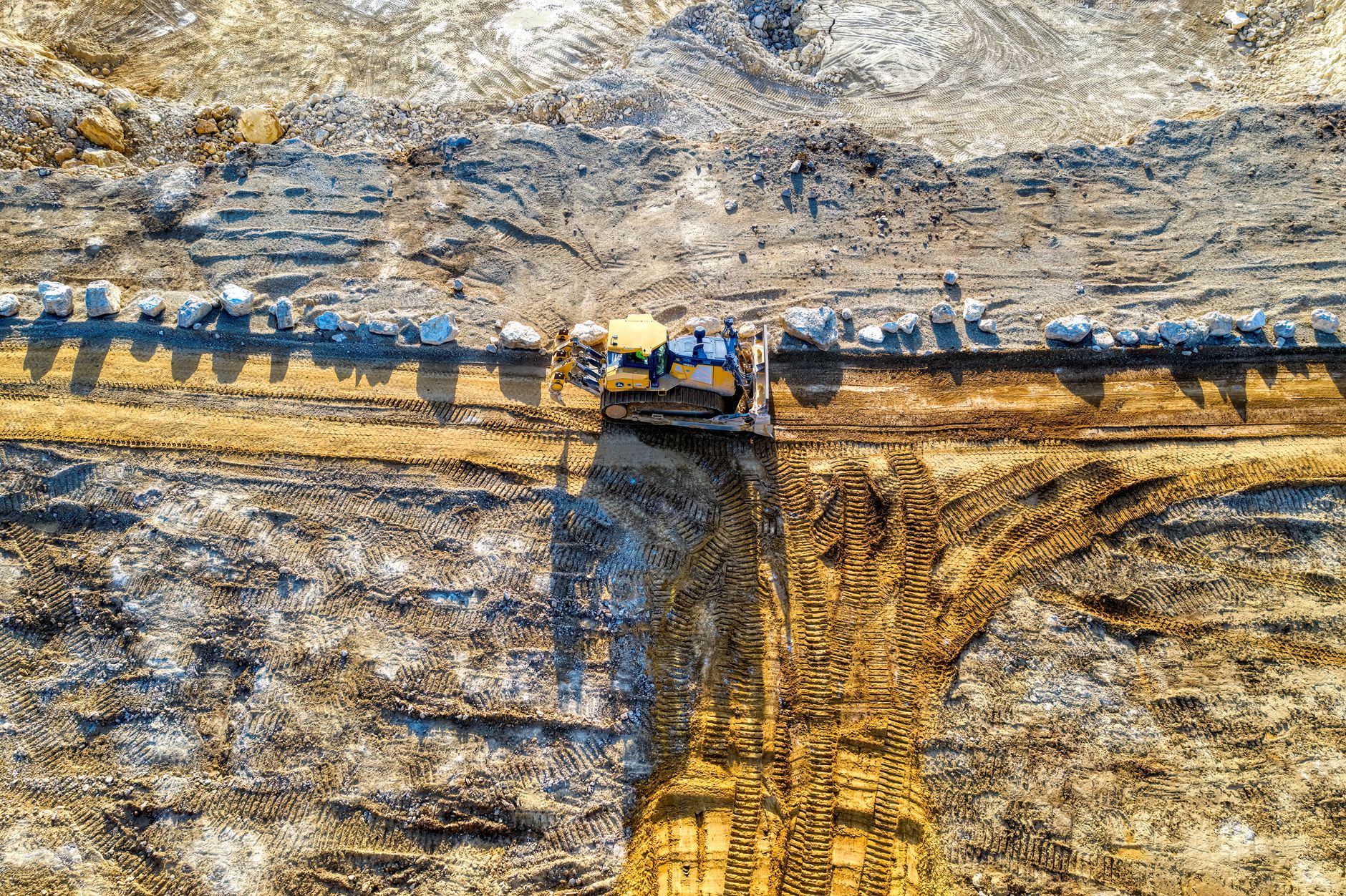 Aerial shot of bulldozer in action at a sandy construction site.